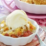 Rhubarb crumble topped with vanilla ice cream in a white ceramic bowl