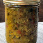 A jar of homemade zucchini relish cooling after being processed by the water bath canning method.