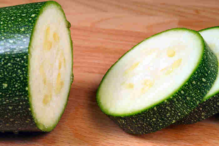 Sliced zucchini 0n a cutting board being prepared for Zucchini Italiano Casserole Recipe