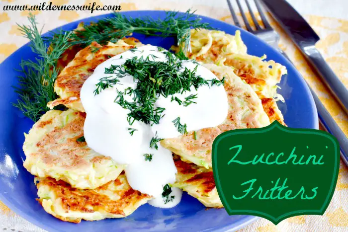 A blue plate loaded with delicious golden brown zucchini fritters drenched in yummy sour cream dill sauce.