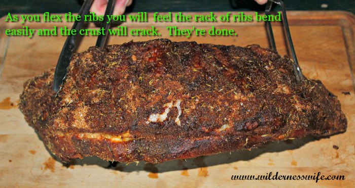 A rack of Extra Tender Pork Back Ribs on wood cutting board being flex tested for doneness.