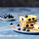 Stack of No-Bake Blueberry Cheesecake Bars on a grey plate sprinkled with lemon zest