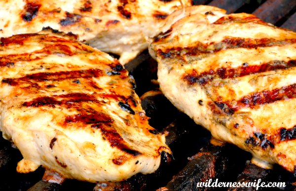 Marinated boneless chicken breasts grilling on a gas grill. They were marinated in my best grilled chicken marinade that is so easy as it has just 2 ingredients - beer and olive oil.