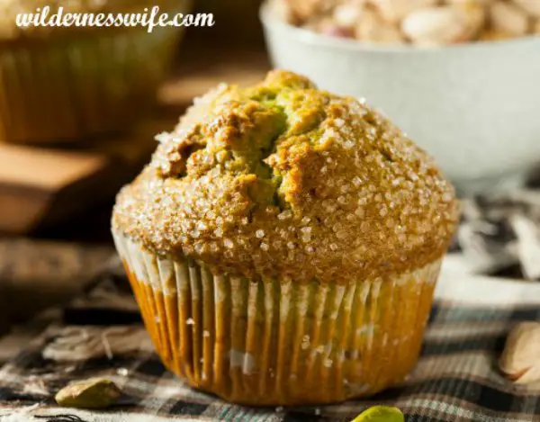 Close-up of a coarse sugar sprinkled pistachio muffin on a checkered kitchen towel