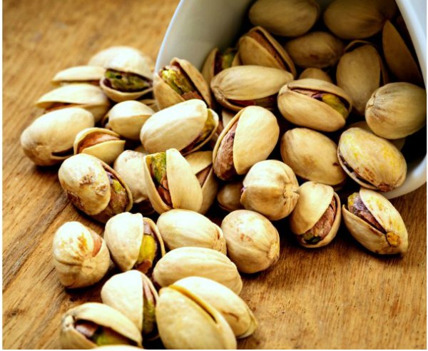 Tipped over Bowl of pistachios spilling out onto cutting board ready to be shucked and chopped for quick and easy pistachio muffin recipe