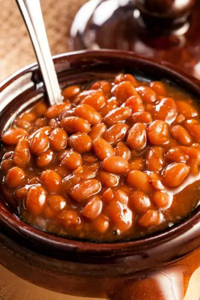 Close-up of baked beans in beanpot with serving spoon in pot