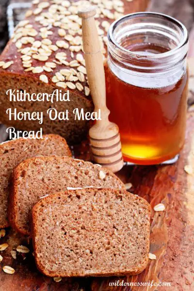 Slices of KitchenAid Honey Oatmeal Bread on a cutting board with bread loaf and honey.