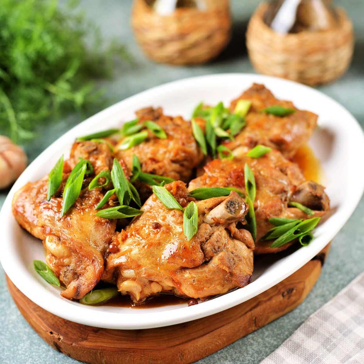 Chicken thighs in creamy mustard sauce  in white dish garnished with scallion tops