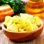 brown bowl full of microwave herbed potatoes sitting on a wooden tabletop