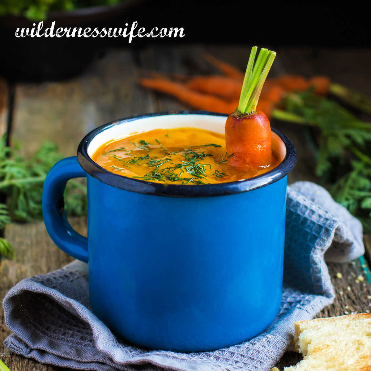 Blue mug sitting on a blue linen napkin full of curry carrot soup