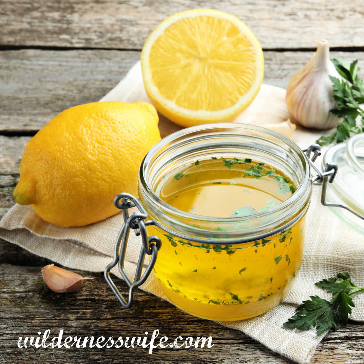 a light cream color napkin spread out on a wooden table with a jar of lemon vinaigrette and a lemon next to it. napkin