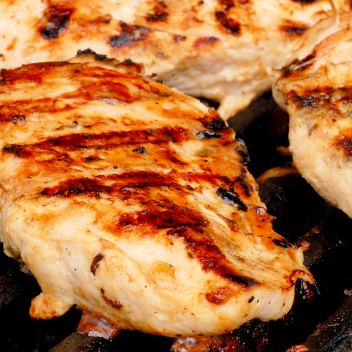 Boneless chicken breasts with grill marks on them on the grill