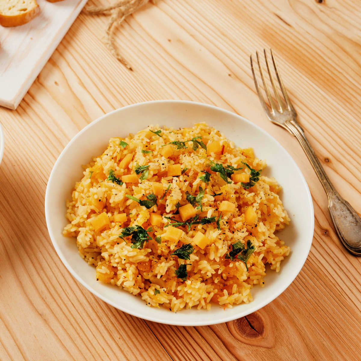 white ceramic bowl full of pumpkin risotto setting on a wooden table