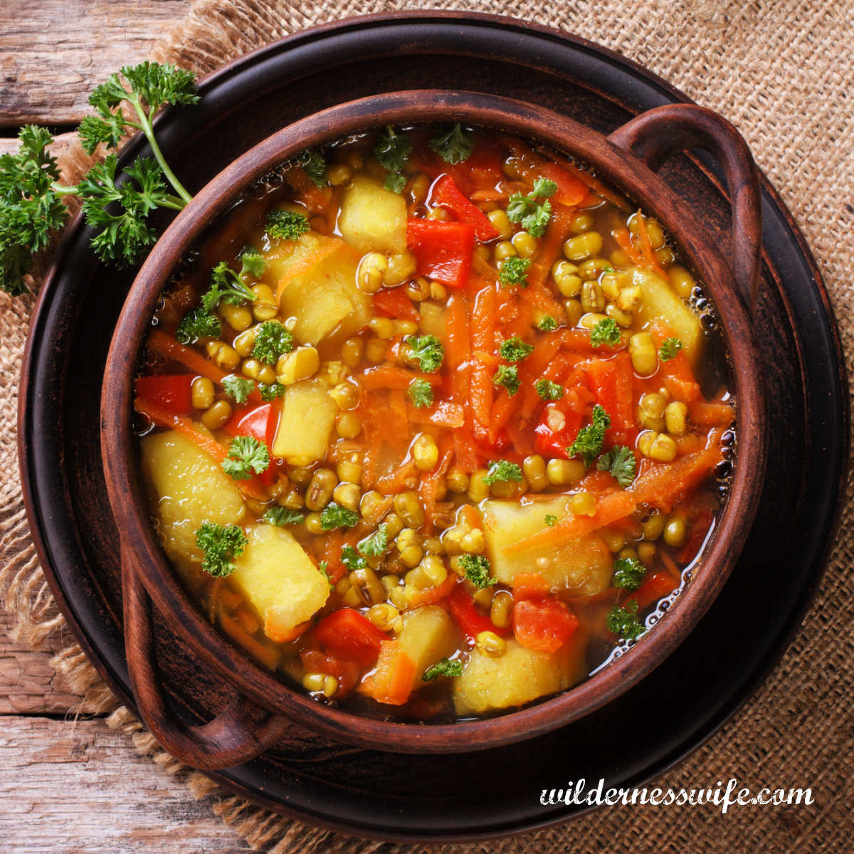 Bowl of vegetable soup in brown earthenware soup bowl.