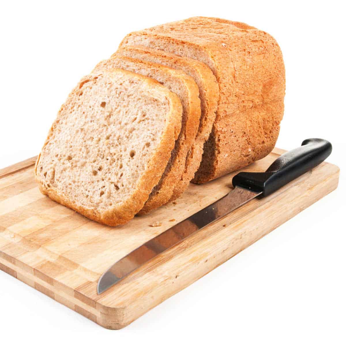 Loaf of Anadama Bread partially sliced on wooden cutting board with serrated knife next to it.