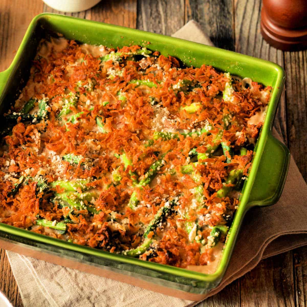 Fiddlehead Casserole in an olive green baking dish sitting on a wooden table