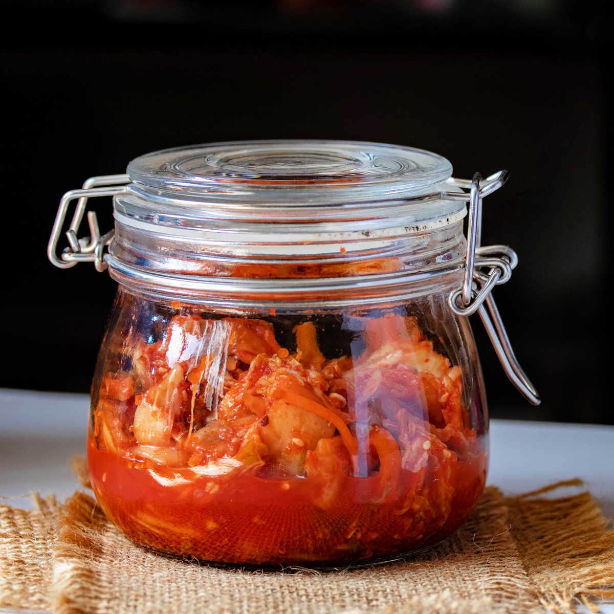 Chunky Pumpkin Chutney in glass canning jar sitting on tan burlap napkin sitting on counter.